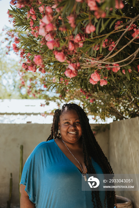 plus size Afro Latinx Haitian American woman smiling under flowering tree looking at camera