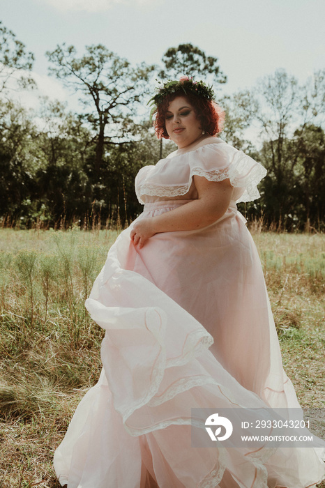 plus size woman walks through field wearing a pink dress