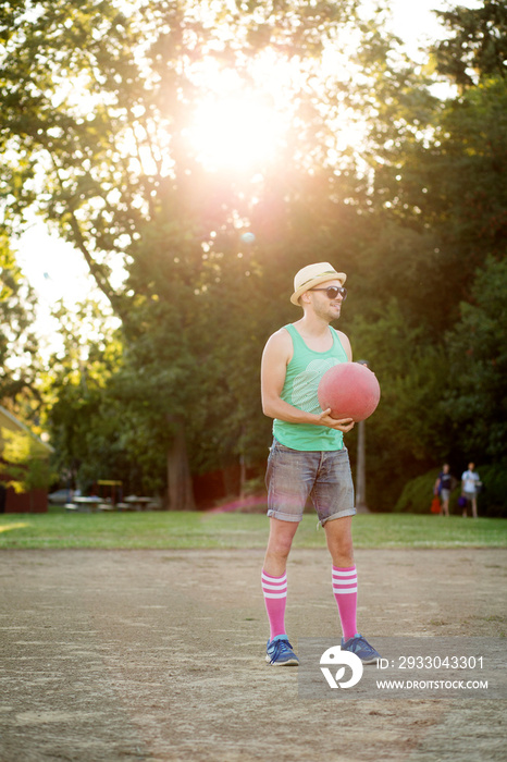 Man holding ball standing in dirt field