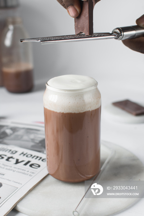 Mocha latte with whipped cream in a can shaped glass,  iced mocha with foam on a table