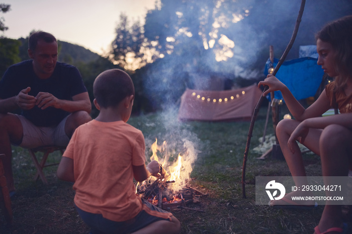 Father with children making a camping fire in the backyard.