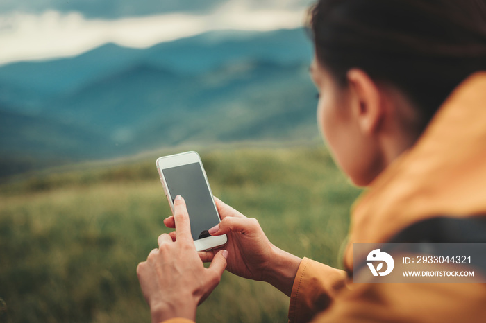 Pleasant young woman using her smartphone while resting outdoors