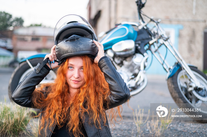 A red-haired woman puts on a helmet for safe motorcycle riding.