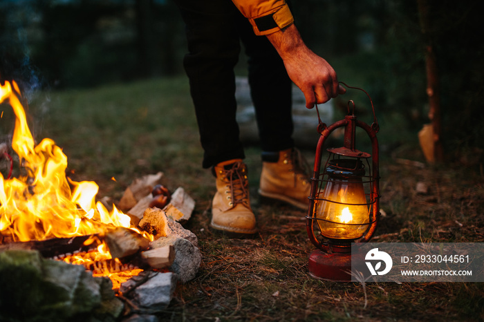 The traveler uses a kerosene lamp. Setting up a shelter in the forest for the night.