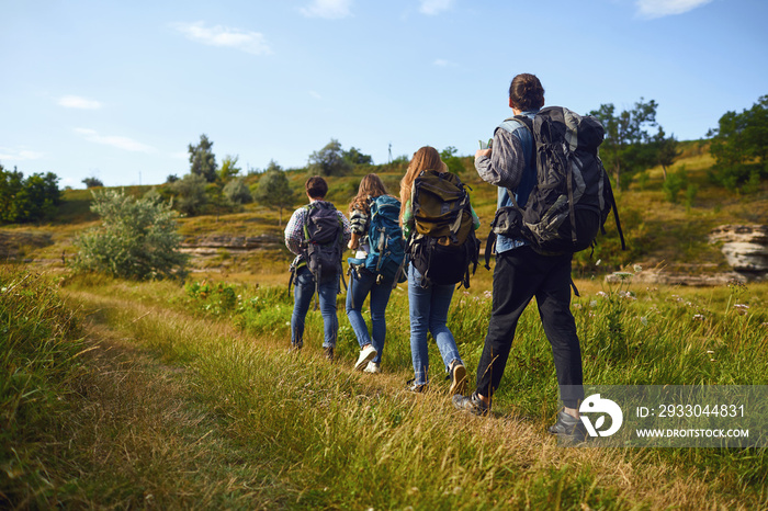 A group of tourists with backpacks is walking in nature