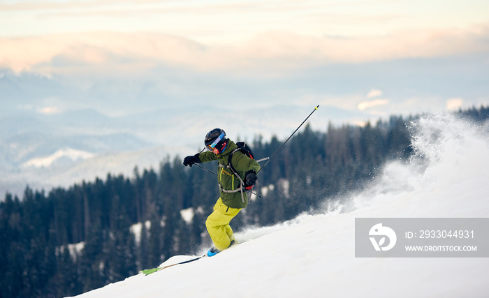 Proficient skier with backpack racing down from high slope. Concept of popular winter extreme amateur sport. Active lifestyle in winter. Amazing nature mountains view from high ski slope. Side view