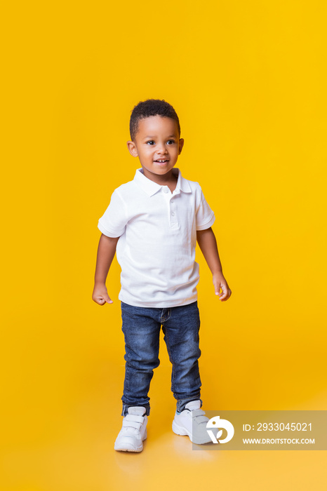 Portrait of smiling little black boy in jeans and white t-shirt