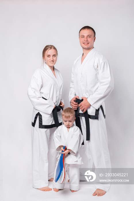 Portrait of happy young family in martial arts uniform standing over white background.