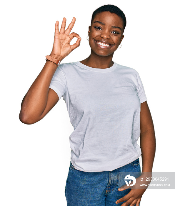 Young african american woman wearing casual white t shirt smiling positive doing ok sign with hand and fingers. successful expression.