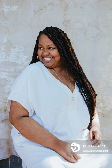 portrait of a plus size afro latinx haitian american woman looking away smiling sitting wearing white