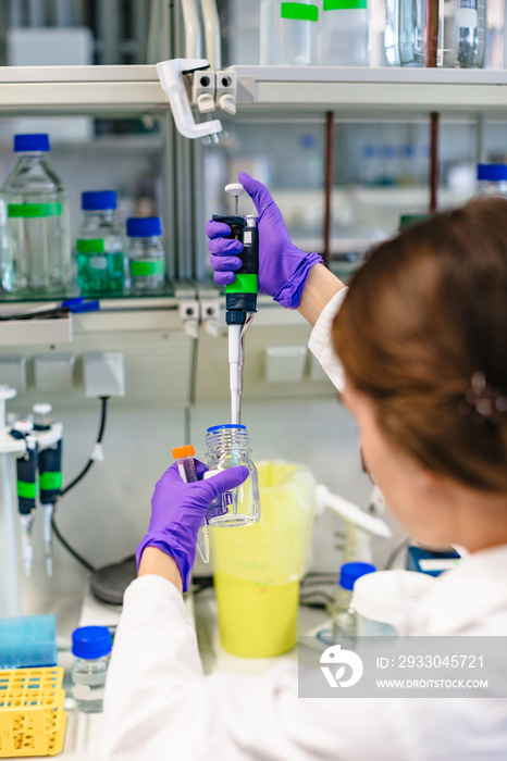 Girl holds test tube and pours liquid into it