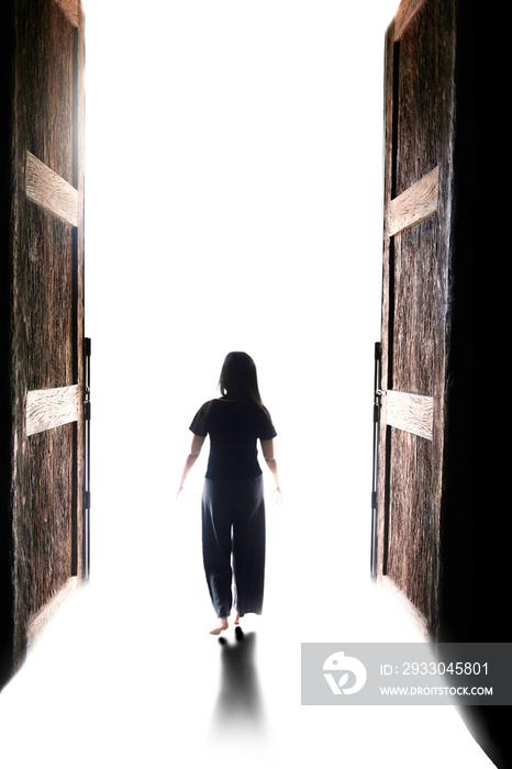 woman walking into the light through open big door