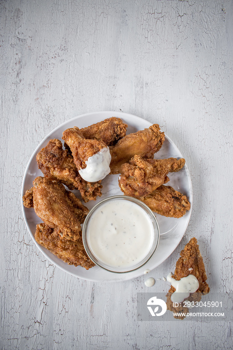 chicken wings with ranch dressing on white plate in bright setting top view