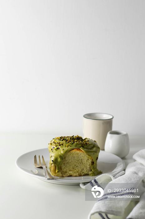 Pistachio spreadable cream cinnamon roll on a white plate. White background.