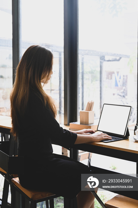 Side view businesswoman working with computer tablet on wooden table near window.