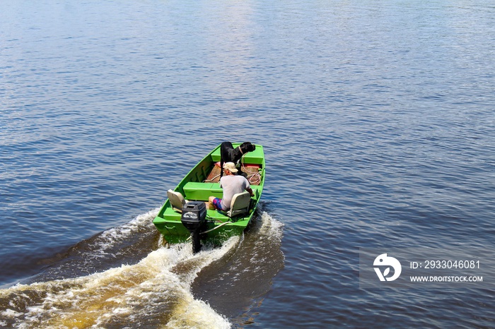 Active senior man enjoying a beautiful day on the Mattaponi River with his Great Dane dog on a green fishing boat