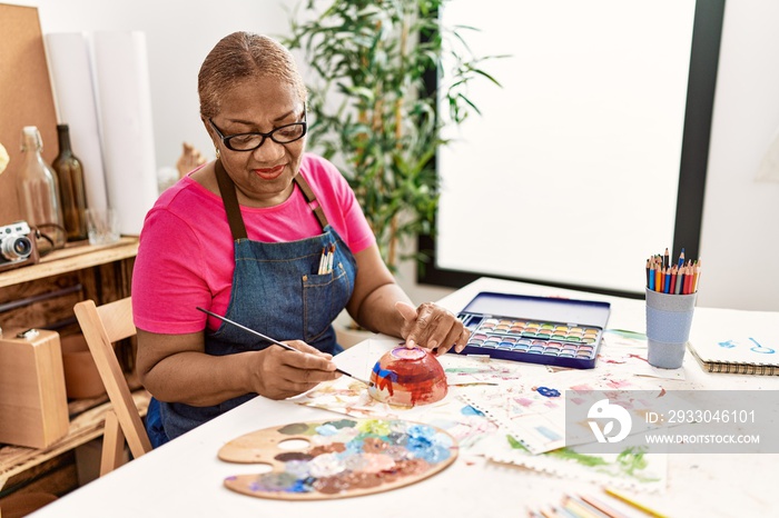 Senior african american woman smiling confident painting clay ceramic at art studio