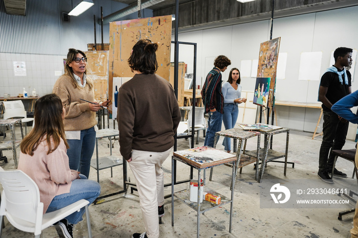 Mature teacher working with art students during painting class at school - Focus on woman face