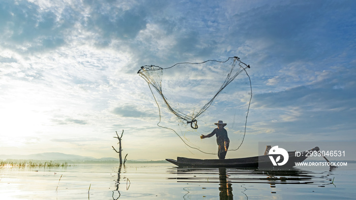 Reflection fisherman action when fishing net with dry alone tree on the boat in the lake outdoors, sunshine morning. Agriculture Industry