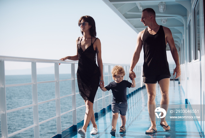 Family travelling on cruise ship on sunny day. Family with cute son on summer vacation. Family rest concept. Father, mother and child walk on deck of cruise liner with sea waves on background.