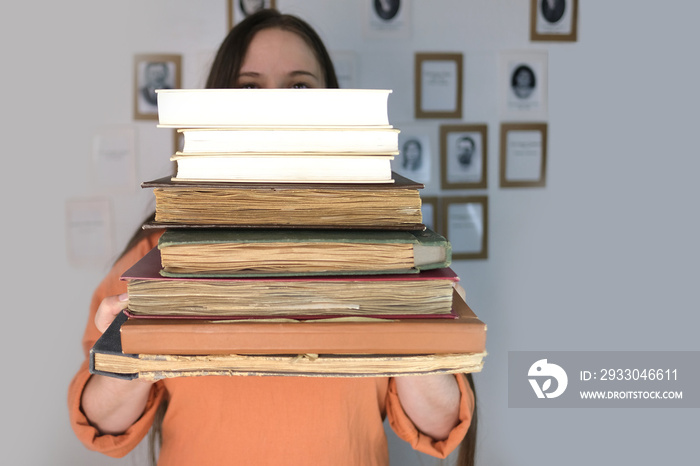 young european woman with long hair holding old thick photo albums, family archive, books, concept of genialogy, memory of ancestors, family tree, childhood memories