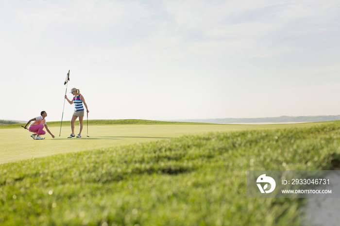 Female golfers putting flag stick back in hole