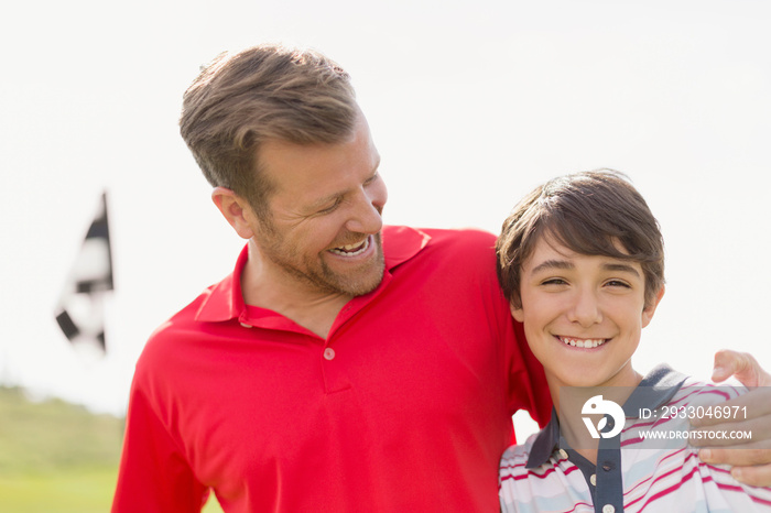 Father with encouraging arm around son on golf course