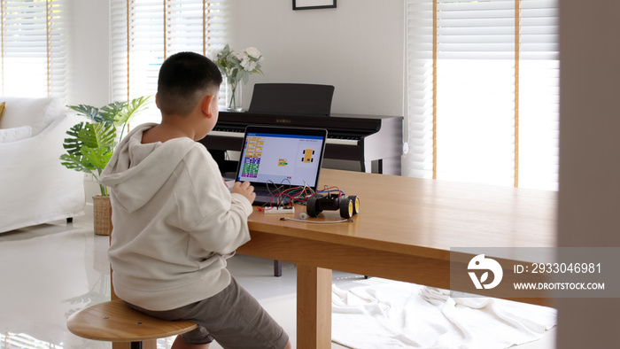 Young asia student remotely learn online at home in coding robot car and electronic board cable in STEM, STEAM, mathematics engineering science technology computer code in robotics for kids concept.