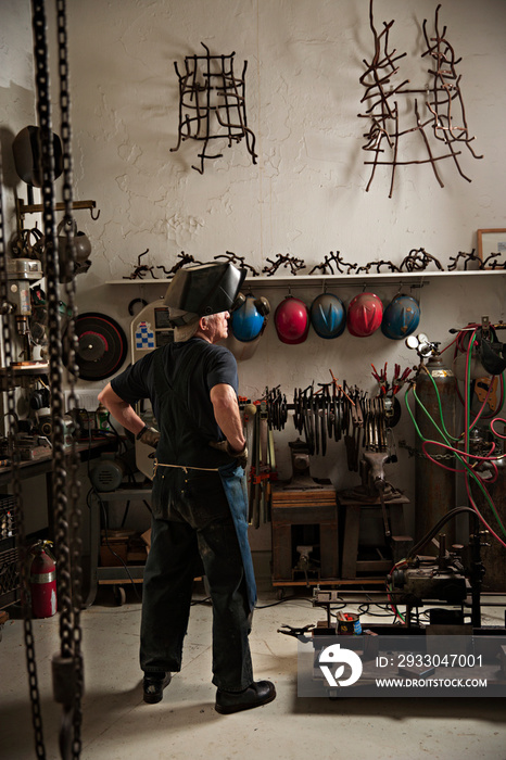 Rear view of senior man with hands on hip in workshop