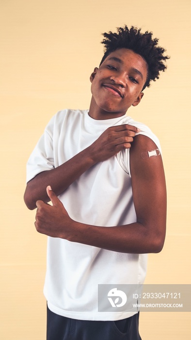 African American teenager showing COVID-19 vaccine bandage merrily in concept of coronavirus vaccination program to vaccinate citizen .