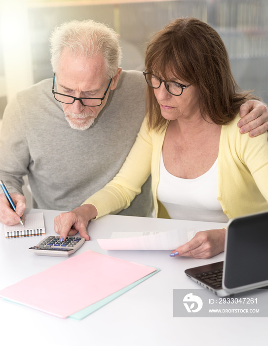 Senior couple checking financial document, light effect