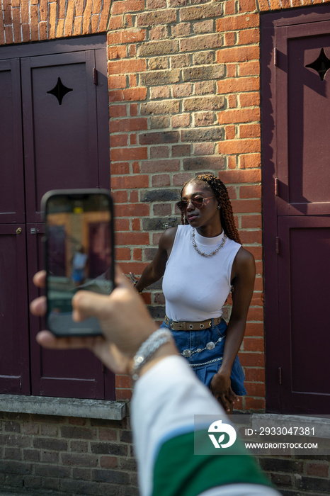 Man photographing fashionable woman with smart phone