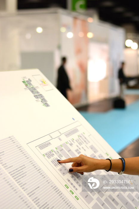 Business woman hand showing on a map at a trade fair