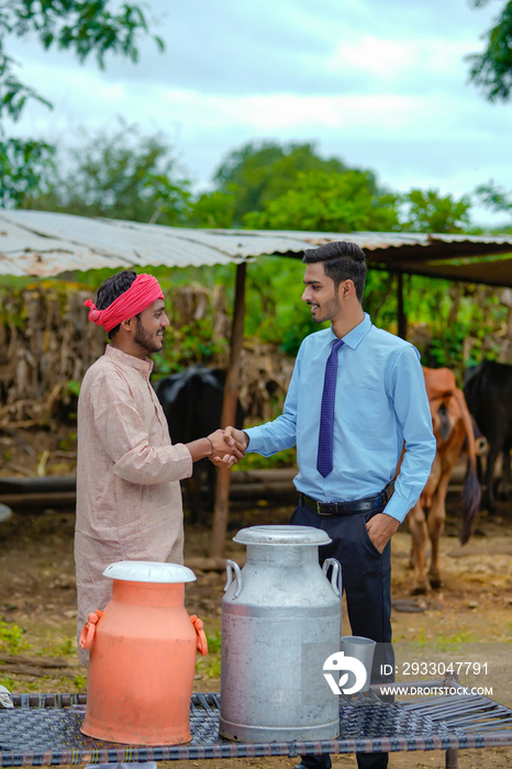 Indian farmer shake hand with agronomist at his cattle farm