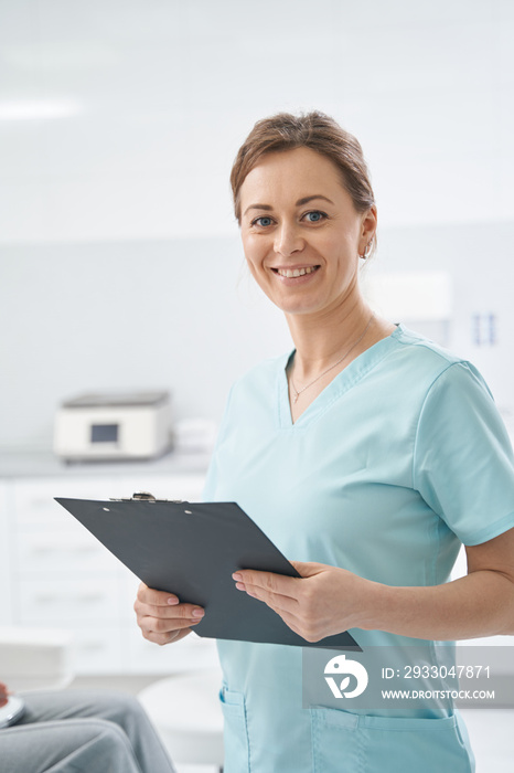 Cheerful woman beautician holding clipboard in beauty salon