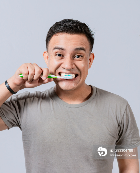 Face of handsome man brushing his teeth. Tooth brushing and care concept. Face of guy brushing teeth isolated. Oral and dental smile concept, Smiling man brushing his teeth isolated