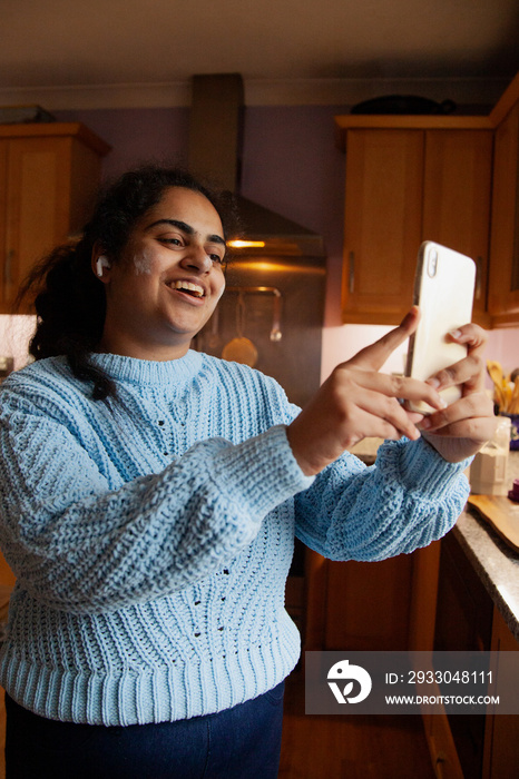 Young curvy woman with Cerebral Palsy taking a selfie while baking in the kitchen