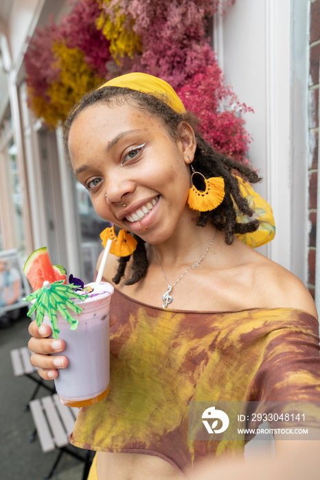 Portrait of young woman drinking smoothie in city