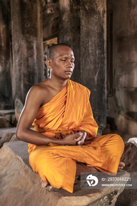 Young buddhist monk meditating in temple in Angkor Wat, Siem Reap, Cambodia