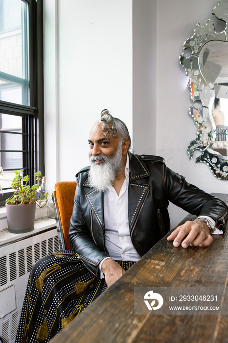 sitting portrait of man with gray beard wearing leather and skirt