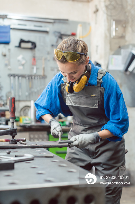 Woman mechanic working in metal workshop