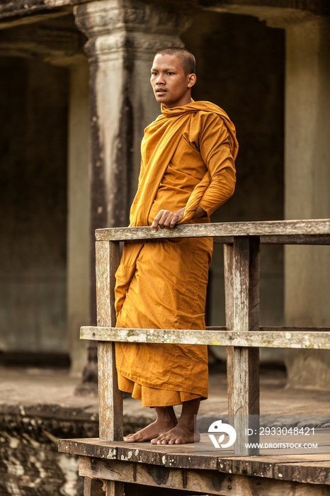 Young Buddhist monk standing by railing in temple, Angkor Wat, Siem Reap, Cambodia