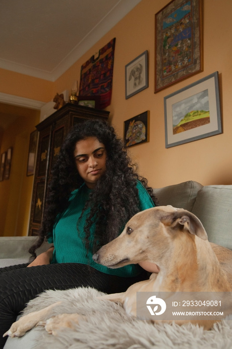 Curvy Indian girl with Cerebral Palsy cuddling her dog in the living room