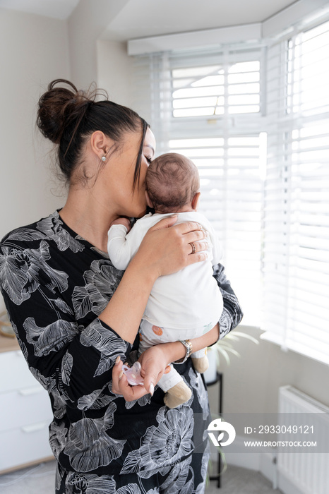 Mother carrying newborn baby girl at home