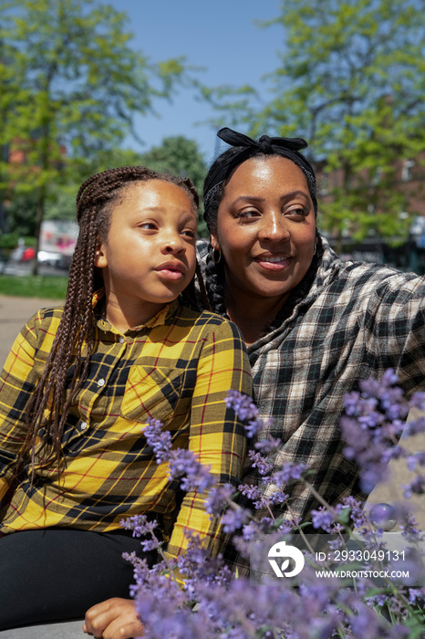 Mother and daughter (6-7) sitting on bench in park