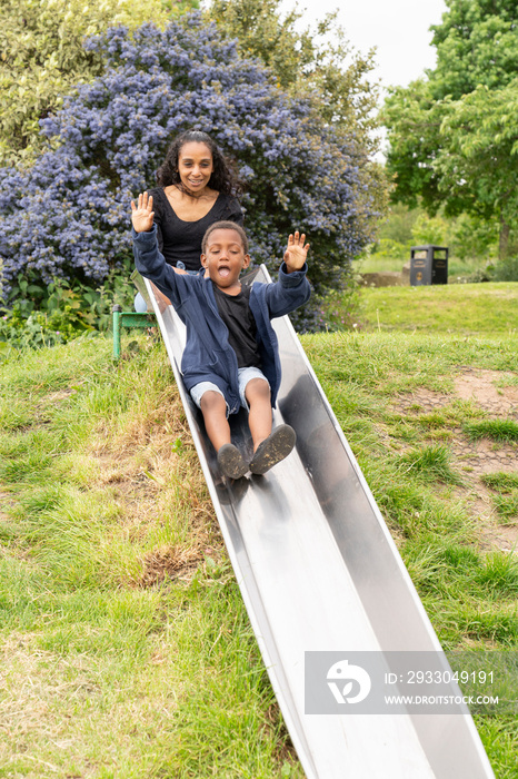 Mother and son having fun on slide at playground