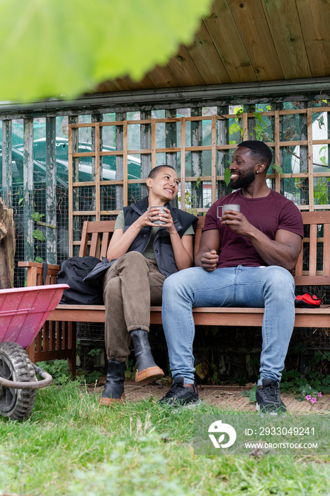 Smiling couple with metal mugs relaxing in urban garden