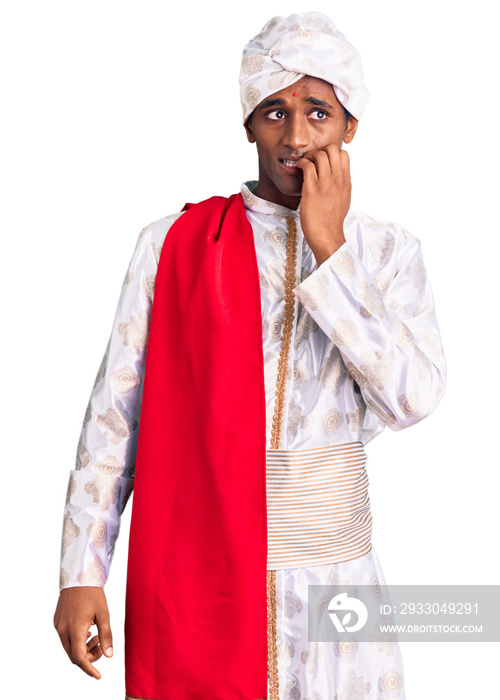 African handsome man wearing tradition sherwani saree clothes looking stressed and nervous with hands on mouth biting nails. anxiety problem.