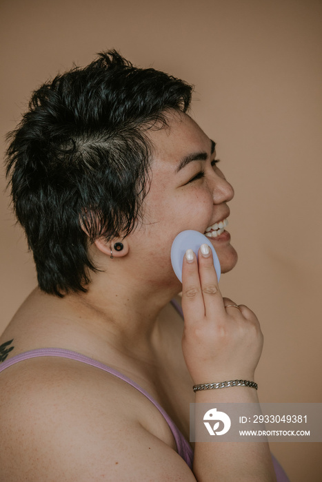 portrait of a plus size woman applying sponge to skin