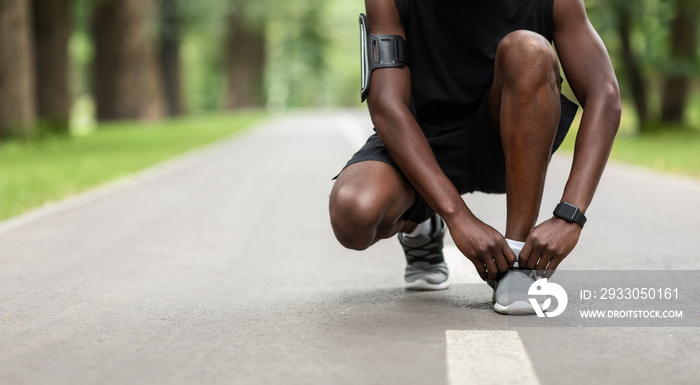 Unrecognizable african man tying his shoelaces on the street